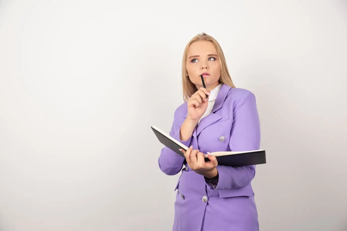 A thoughtful woman with an open tablet and a pencil on a white background.