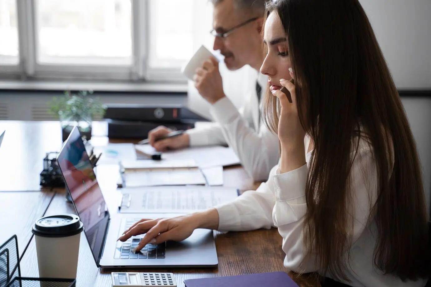 People working at a desk, seen from the side.